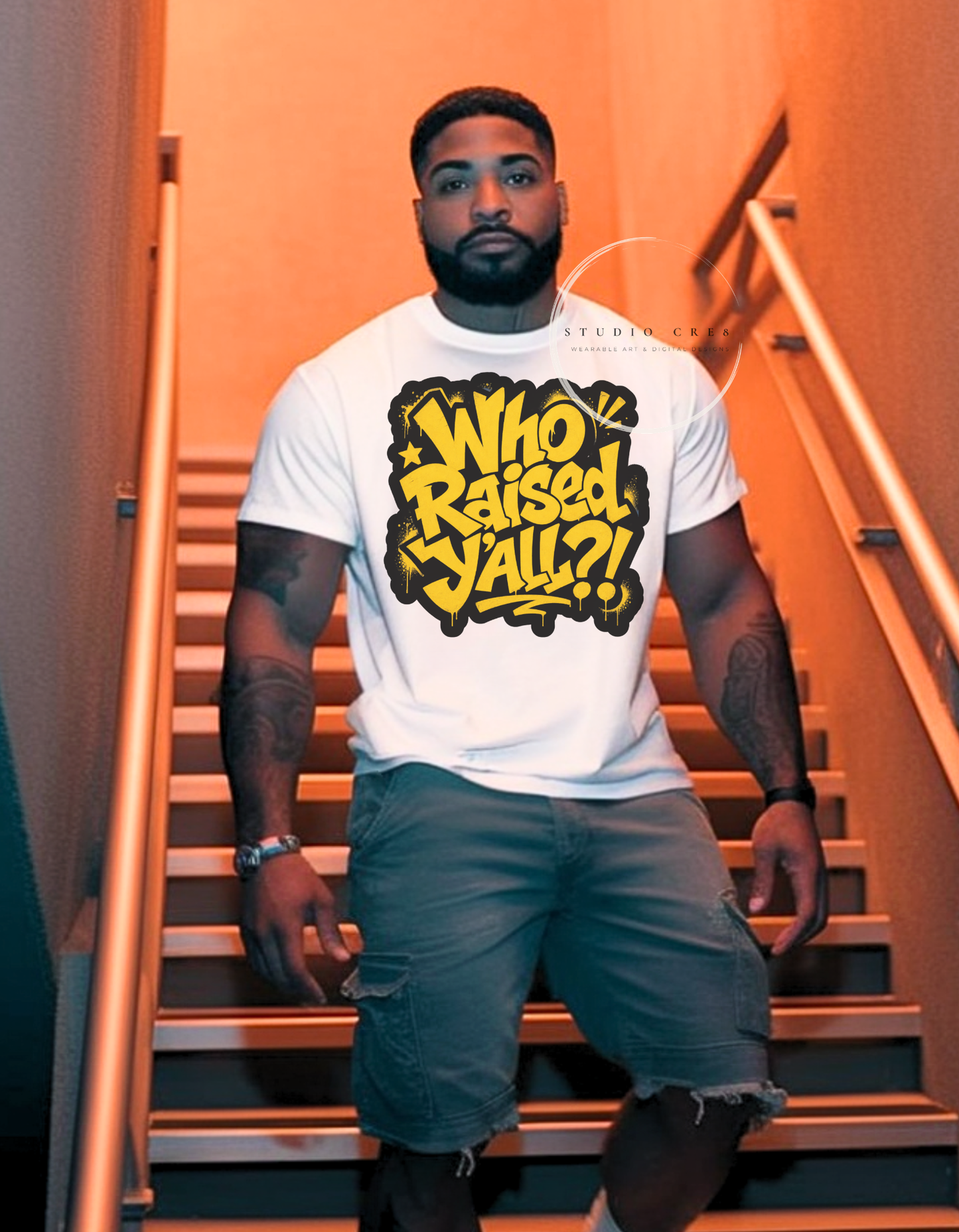 Man on stairs, wearing a white t-shirt with a graphic design graffiti style text that says "Who Raised Y'all?!"