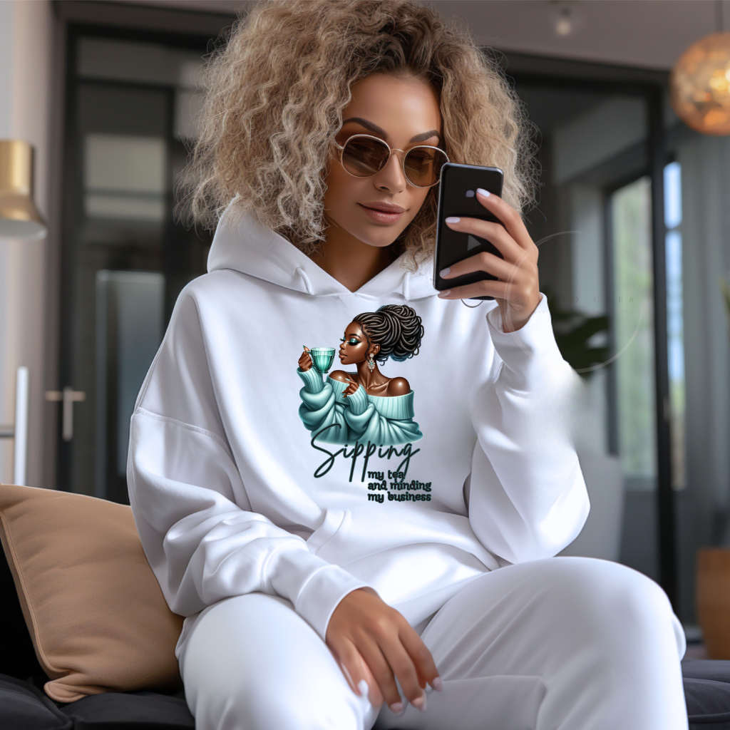 Woman wearing a white hoodie with a graphic design, sitting on a couch in a modern living room.