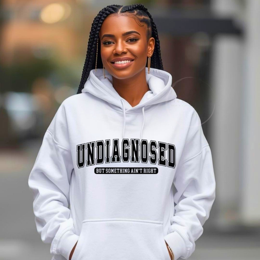 Person wearing a white hoodie with 'UNDiAGNOSED' text, standing outdoors.